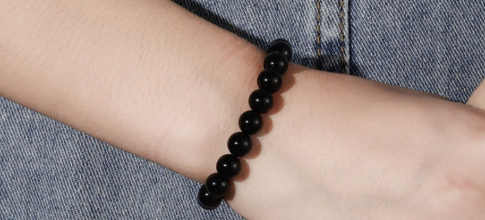 Bracelet en agate noire tenu dans la paume d'une main