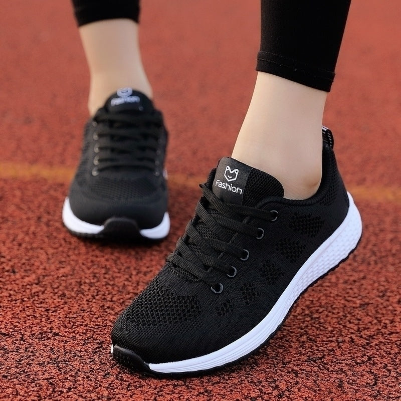 Baskets femme en maille noires, portées sur une piste d'athlétisme
