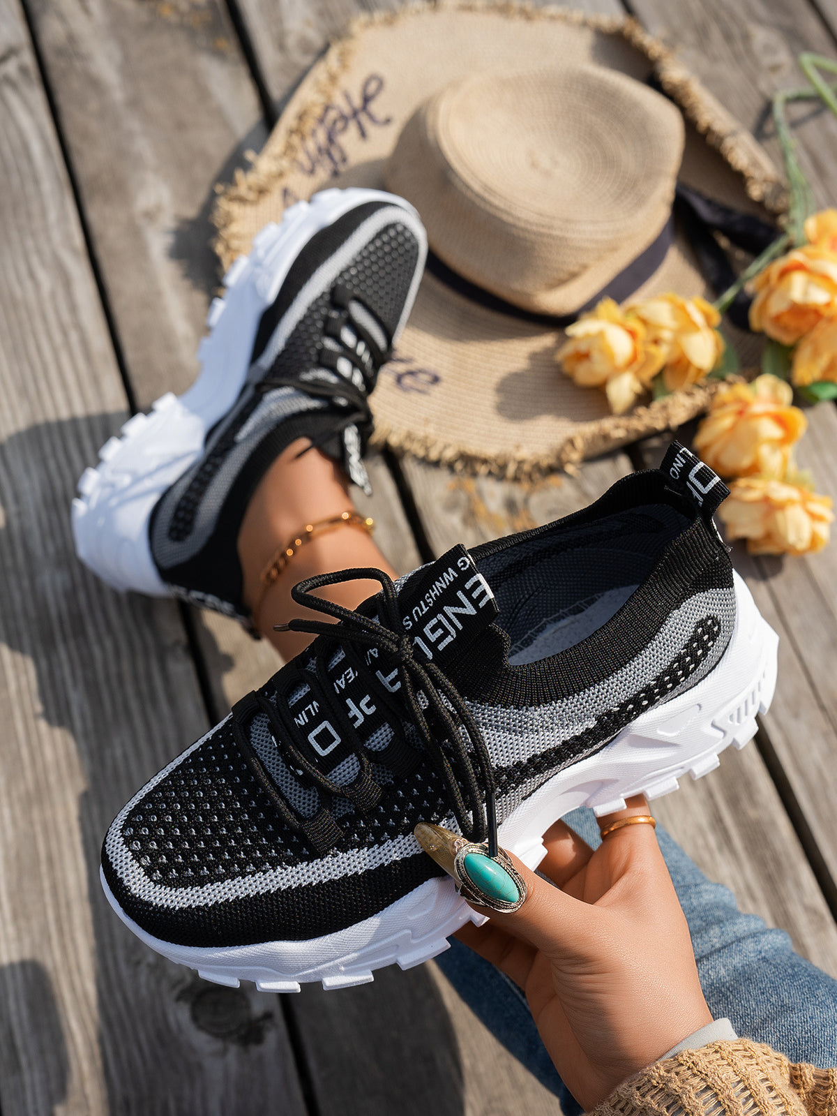 Baskets en maille noire tenues à la main