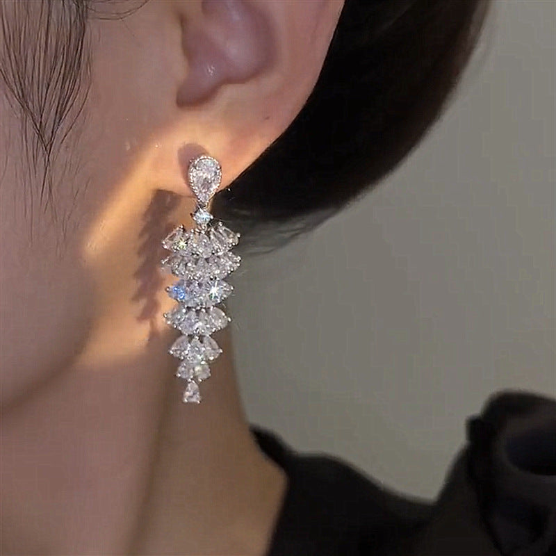 Boucles d'oreilles en zircons tenues à la main, rangs étagés visibles