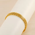 Bracelet maille doré présenté sur un support cylindrique