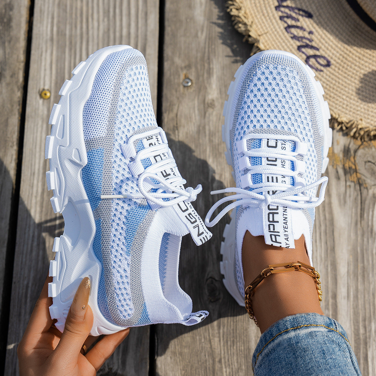 Baskets en maille blanche et bleue tenues à la main