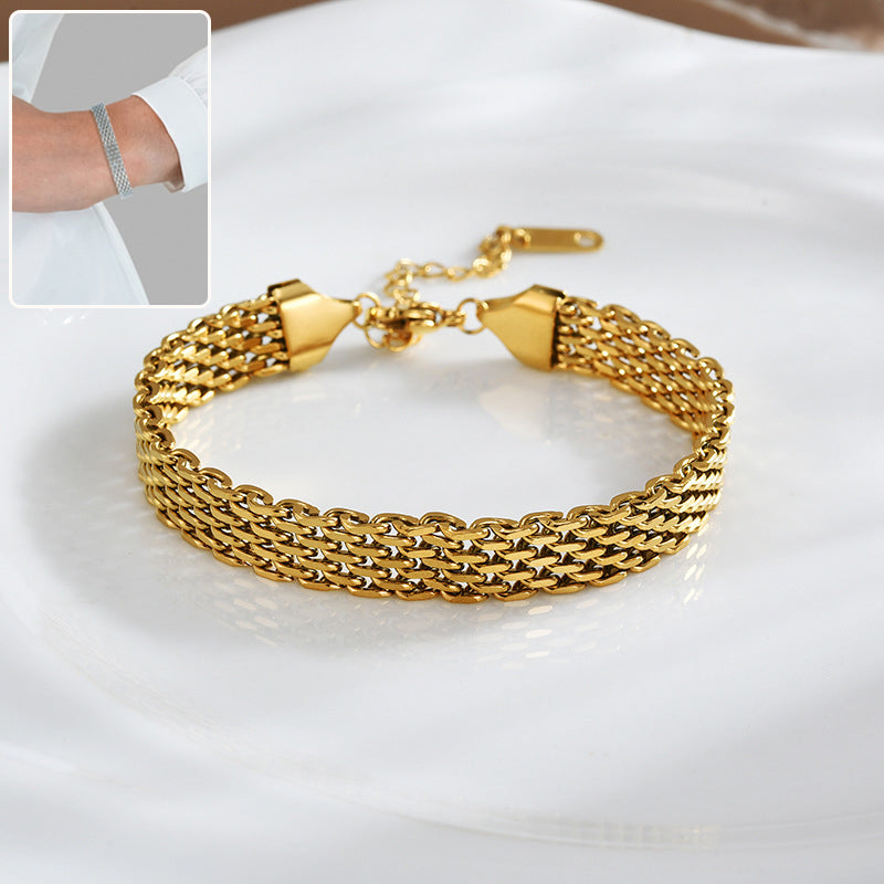 Bracelet maille doré posé sur un tissu blanc